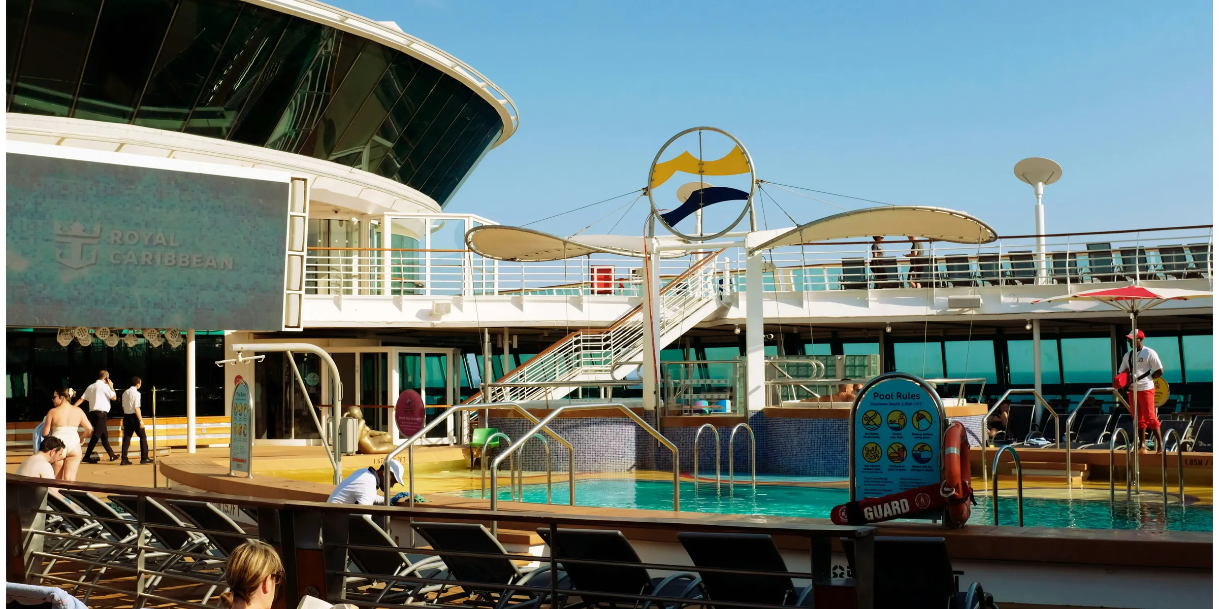 People relaxing on lounge chairs by a cruise ship pool.