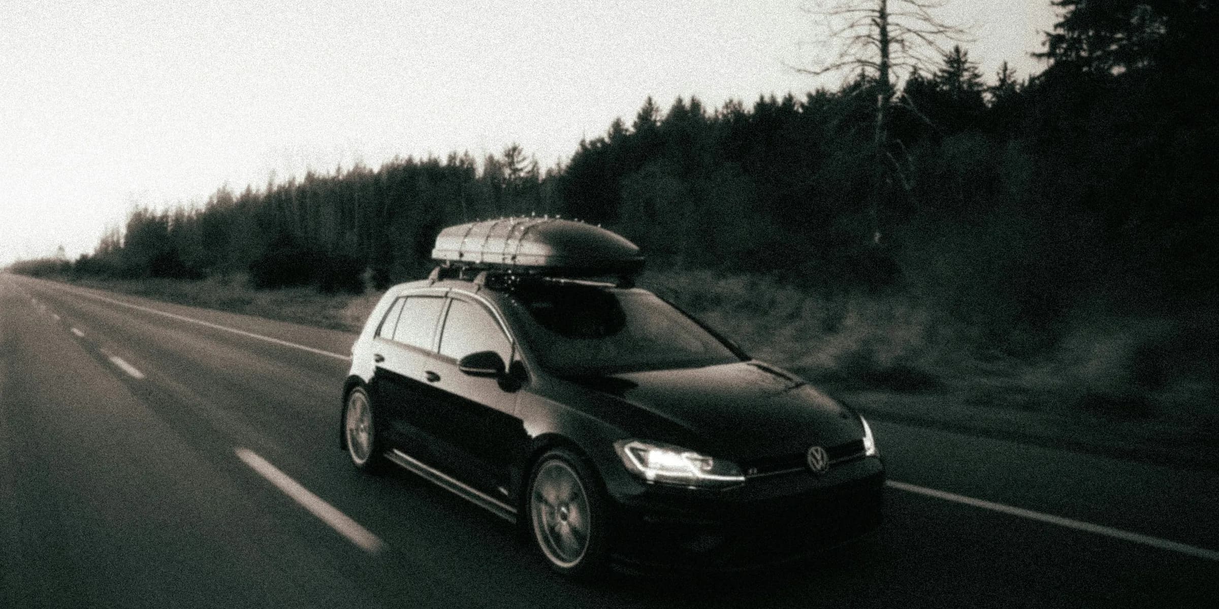 a car driving down a road with a surfboard on top of it