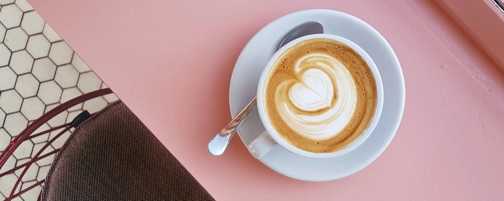 Photo of a latte with a heart design on a pink counter